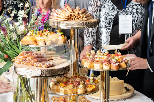 Image of Businesspeople at banquet lunch break at business conference meeting. Assortment of canapes and finger food on the table.