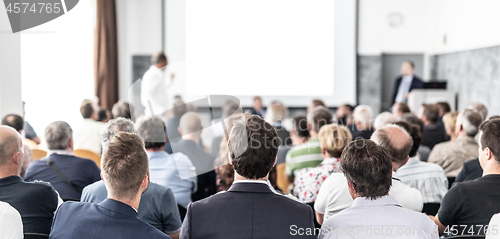 Image of I have a question. Group of business people sitting in conference hall. Businessman raising his arm. Conference and Presentation. Business and Entrepreneurship