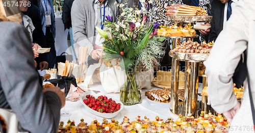 Image of Businesspeople at banquet lunch break at business conference meeting. Assortment of canapes and finger food on the table.