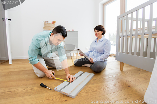 Image of family couple assembling baby bed at home