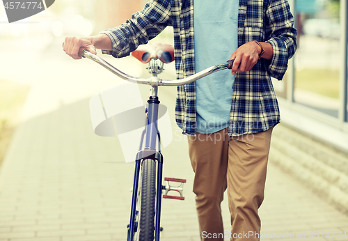 Image of close up of man with bicycle walking along city