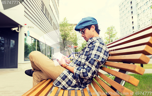 Image of man with notebook or diary writing on city street