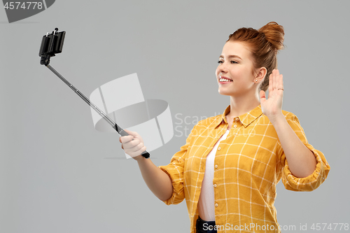 Image of happy teenage girl taking picture by selfie stick