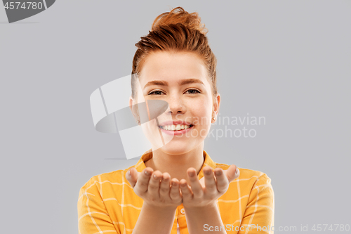 Image of happy red haired teenage girl holding empty hands