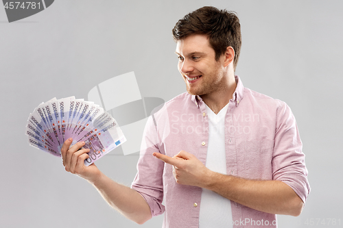 Image of smiling young man showing fan of euro money