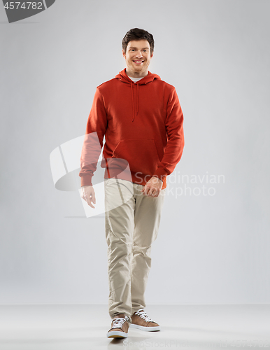 Image of young man in red hoodie walking over grey