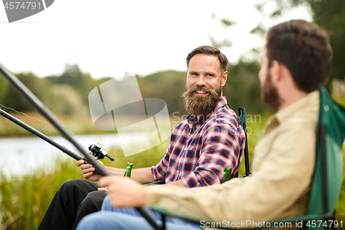 Image of happy friends with fishing rods on lake