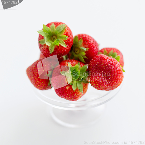Image of strawberries on glass stand over white background
