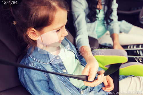 Image of happy woman fastening child with seat belt in car