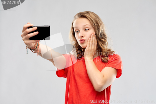 Image of smiling teenage girl taking selfie by smartphone