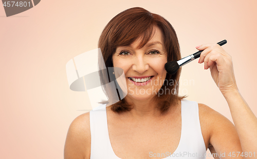 Image of smiling senior woman with make up blush brush