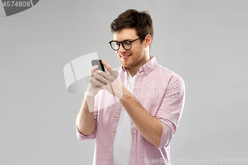 Image of young man in glasses looking at smartphone