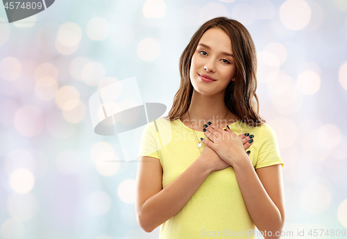 Image of smiling teenage girl holding hands on heart