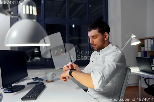 Image of businessman using smart watch at nigh office