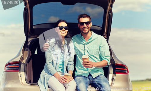 Image of happy couple with coffee at hatchback car trunk