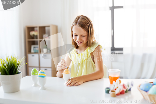 Image of happy girl coloring easter eggs at home