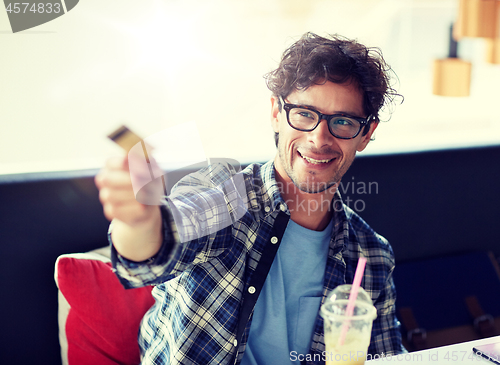 Image of happy man paying with credit card at cafe