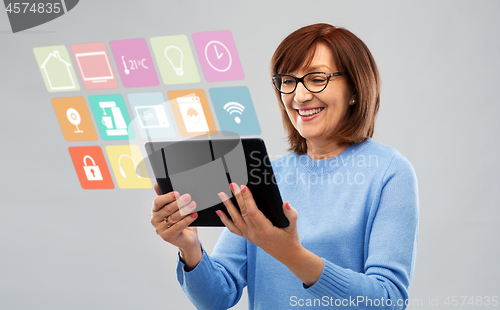 Image of senior woman with tablet pc using smart home app