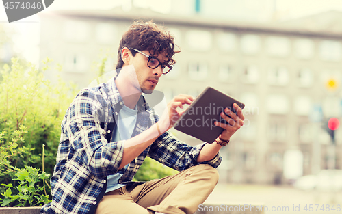 Image of man with tablet pc sitting on city street bench