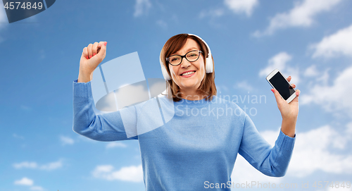 Image of senior woman in headphones listening music on cell