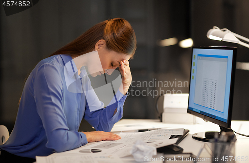 Image of tired businesswoman with computer at night office