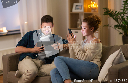 Image of couple with tablet computer and smartphone at home