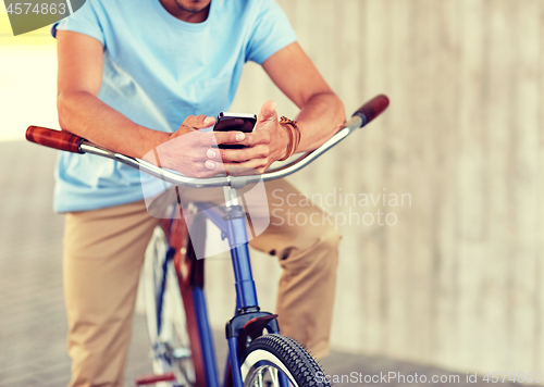 Image of close up of man with smartphone and bike on street