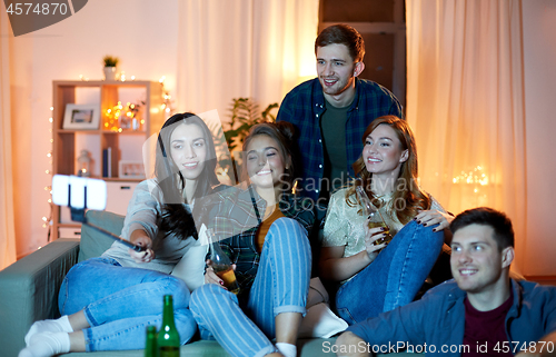 Image of friends taking picture by selfie stick at home