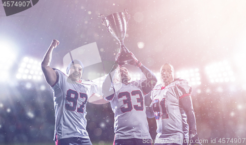 Image of american football team with trophy celebrating victory in the cu