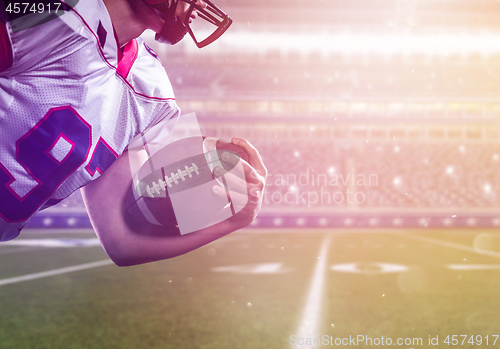 Image of American football player holding ball while running on the field