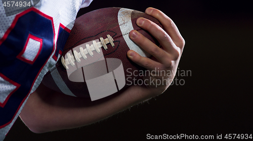 Image of American football player holding ball while running on field