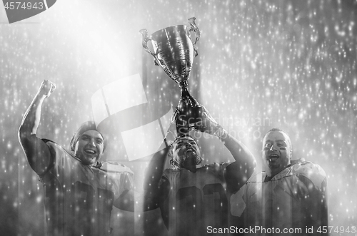 Image of american football team with trophy celebrating victory in the cu