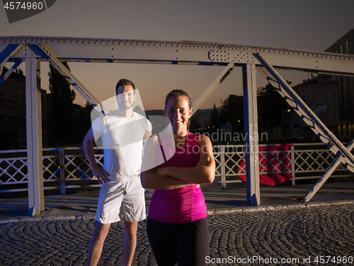 Image of portrait of couple jogging across the bridge in the city