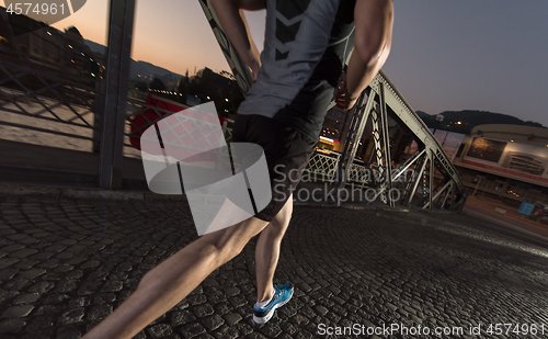 Image of man jogging across the bridge in the city