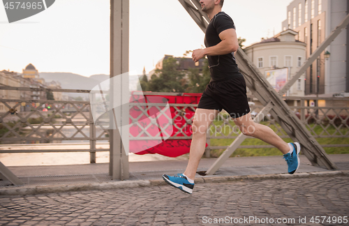 Image of man jogging across the bridge at sunny morning