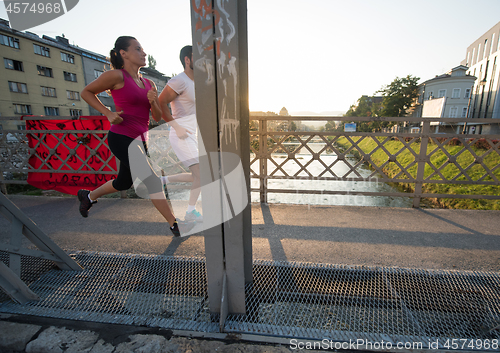 Image of young couple jogging across the bridge in the city