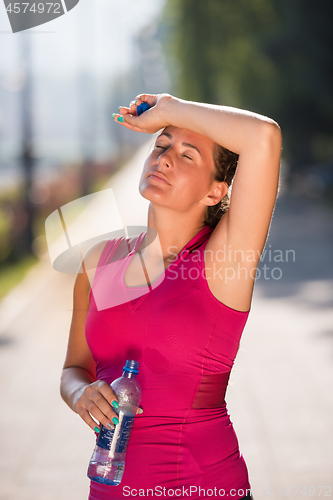 Image of woman drinking water from a bottle after jogging