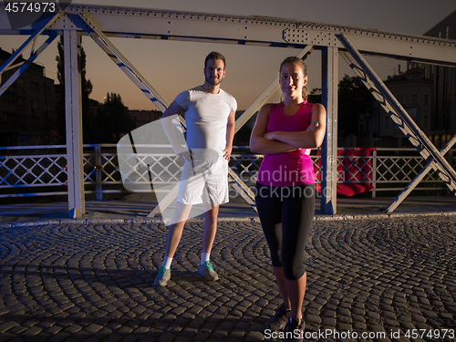 Image of portrait of couple jogging across the bridge in the city