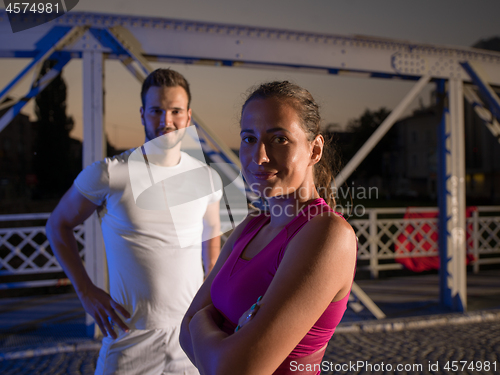 Image of portrait of couple jogging across the bridge in the city