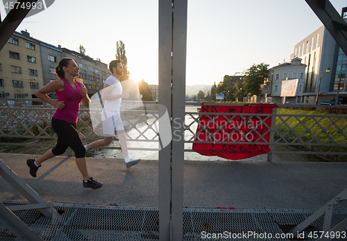 Image of young couple jogging across the bridge in the city