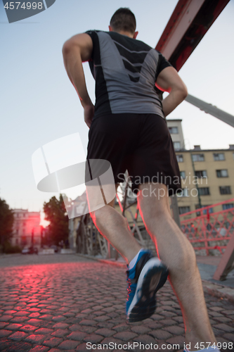 Image of man jogging across the bridge at sunny morning