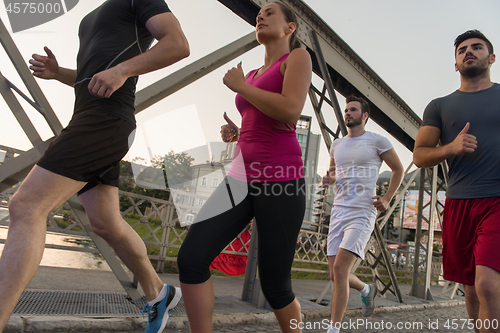 Image of group of young people jogging across the bridge