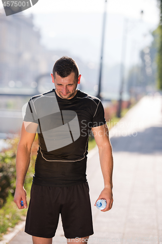 Image of man pouring water from bottle on his head