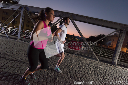 Image of couple jogging across the bridge in the city