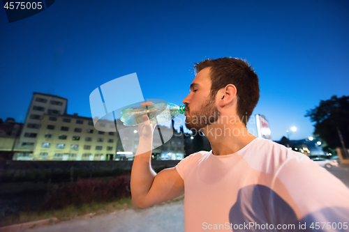 Image of man drinking water after running session