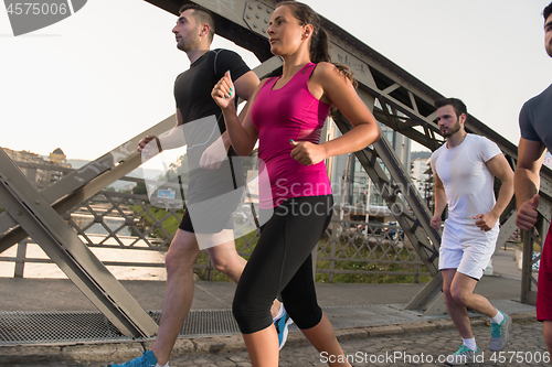 Image of group of young people jogging across the bridge