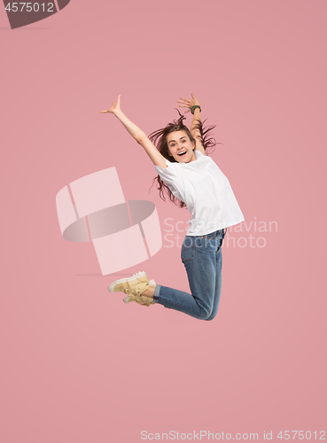 Image of Freedom in moving. Pretty young woman jumping against pink background