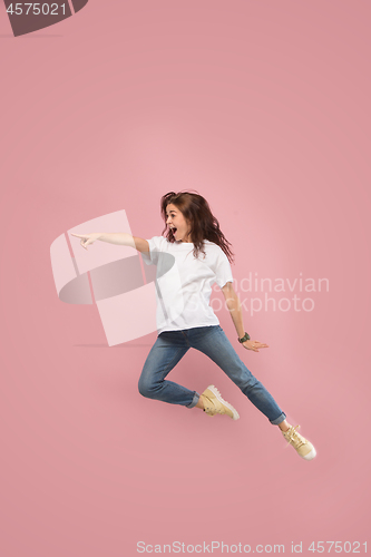 Image of Freedom in moving. Pretty young woman jumping against pink background