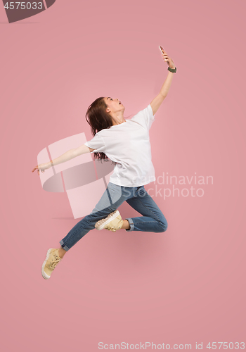 Image of Full length of pretty young woman with mobile phone while jumping