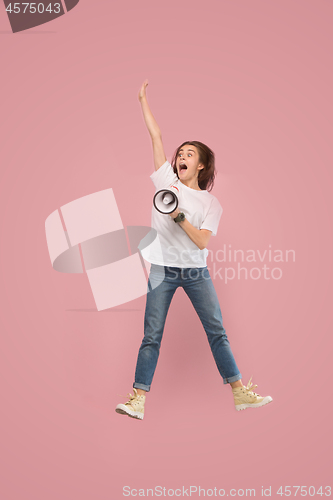 Image of Beautiful young woman jumping with megaphone isolated over pink background